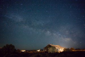 Ein atemberaubendes Sternenmeer breitet am Nachthimmel über einem Safari-Zelt aus.