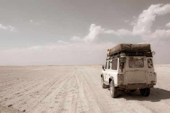 Ein Jeep fährt durch die Wüstenlandschaft in Botswana