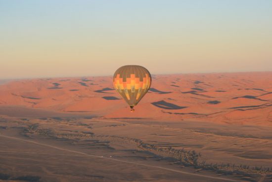 Ein Heißluftballon schwebt über den roten Dünen der Namib