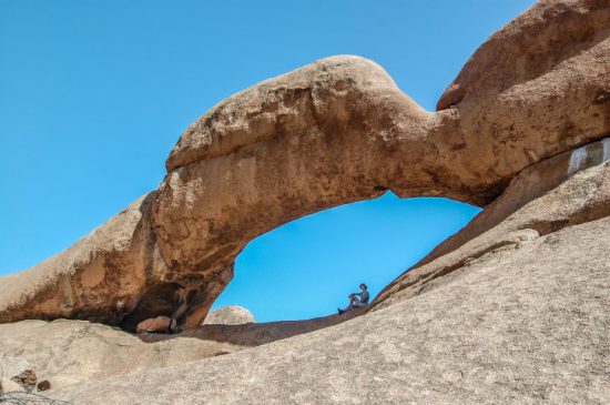 Frau sitzt zwischen Felsformationen in Spitzkoppe, Namibia