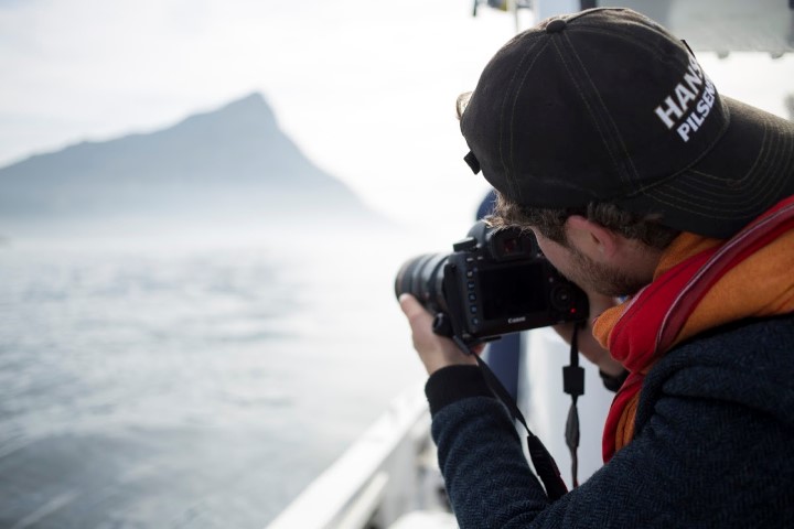 Ein Mann auf einem Boot macht ein Foto von Südafrikas nebliger Küste