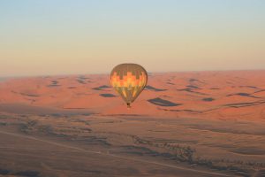 Ein Heißluftballon schwebt über den roten Dünen der Namib